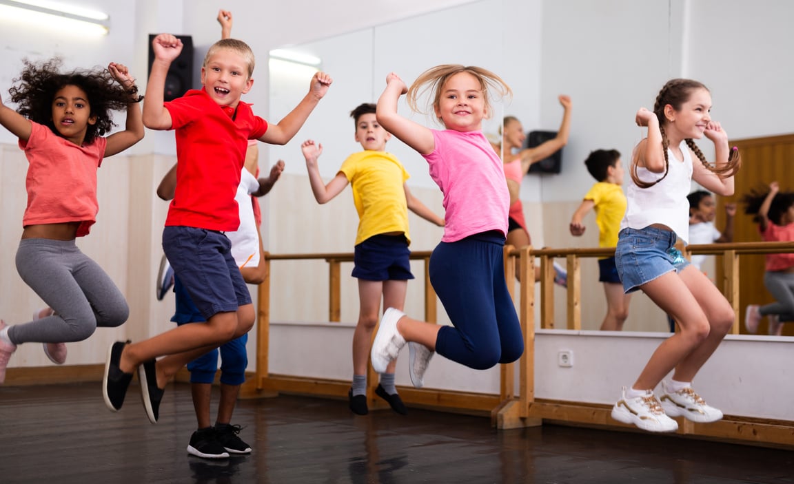 Happy sporty kids jumping together in dance studio