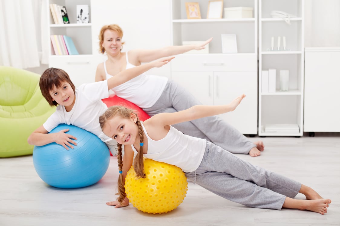 Kids and mother exercising together using exercise balls